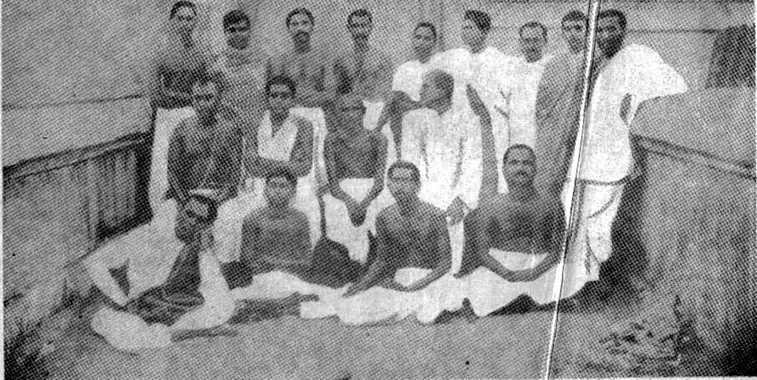 Sri Sri Thakur Anukulchandra standing behind his father Shivchandra Chakravarty, who is seated among devotees