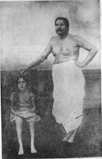 Sri Sri Thakur Anukulchandra standing with his hand on the head of his youngest daughter, Santwana Devi